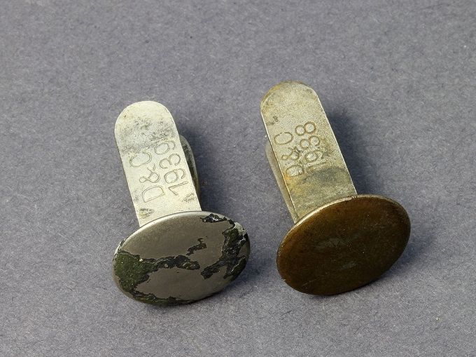 To nagler fra produsent D & C - Dransfeld und Company, Menden. Denne produsenten er den største og leverte nagler til hjelmproduksjon gjennom hele krigen. Naglen til venstre er av aluminium og er datert 1939 og naglen til høyre er av messing og er datert 1938.