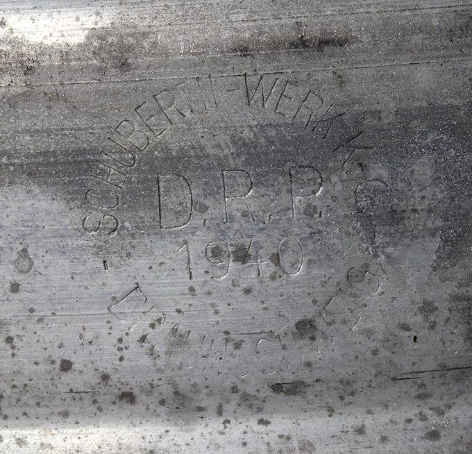 Produsentmerkinger på et sinkbelagt stålbånd datert 1940. Produsenten er den samme som aluminiumsbåndet vist over, nemlig Schuberth-Werk K.-G. fra Braunschweig. 