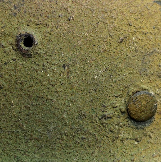 Nærbilde av malingsstrukturen på M35 hjelmen vist over. Legg merke til den grove teksturen med sagspon og sagflis.